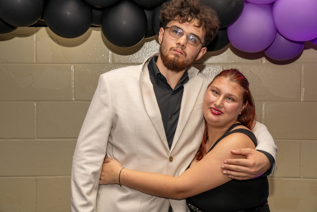A couple is hugging and smiling for a photo together inside the music building. 