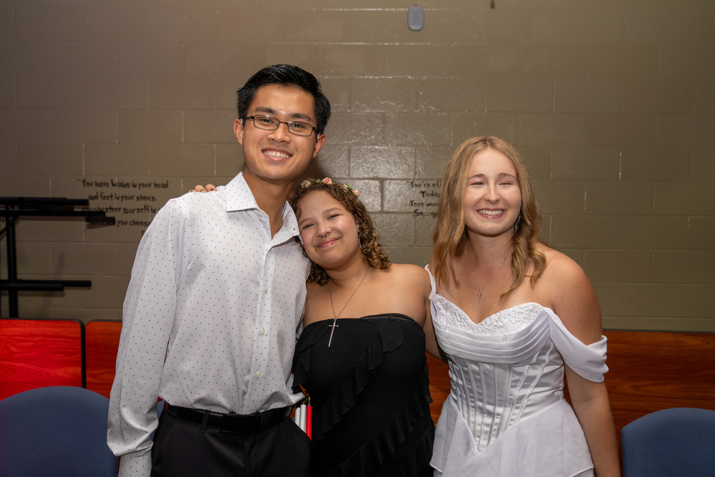 Three friends smile for a photo inside the music building. 