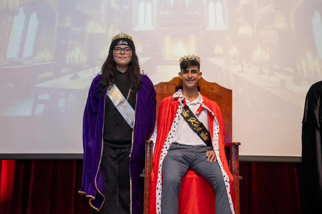 Homecoming Senior Queen and King smile for a photo on stage in the Music Building. 