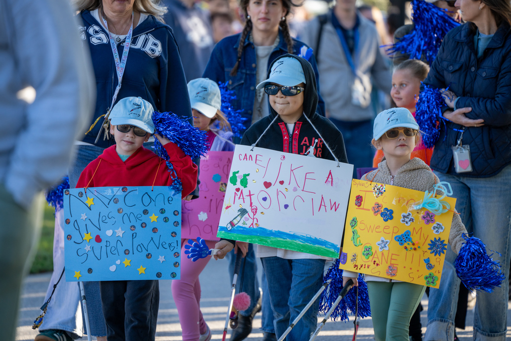 Three students hold a sign around their neck as they walk down the streets of FSDB. 