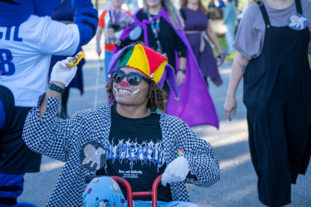 A student is dressed like a clown riding a small bike through the streets of FSDB. 