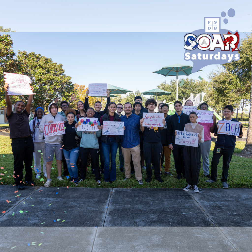 Group photo of Zach with his SOAR Students holding "Congratulations" signs outside.