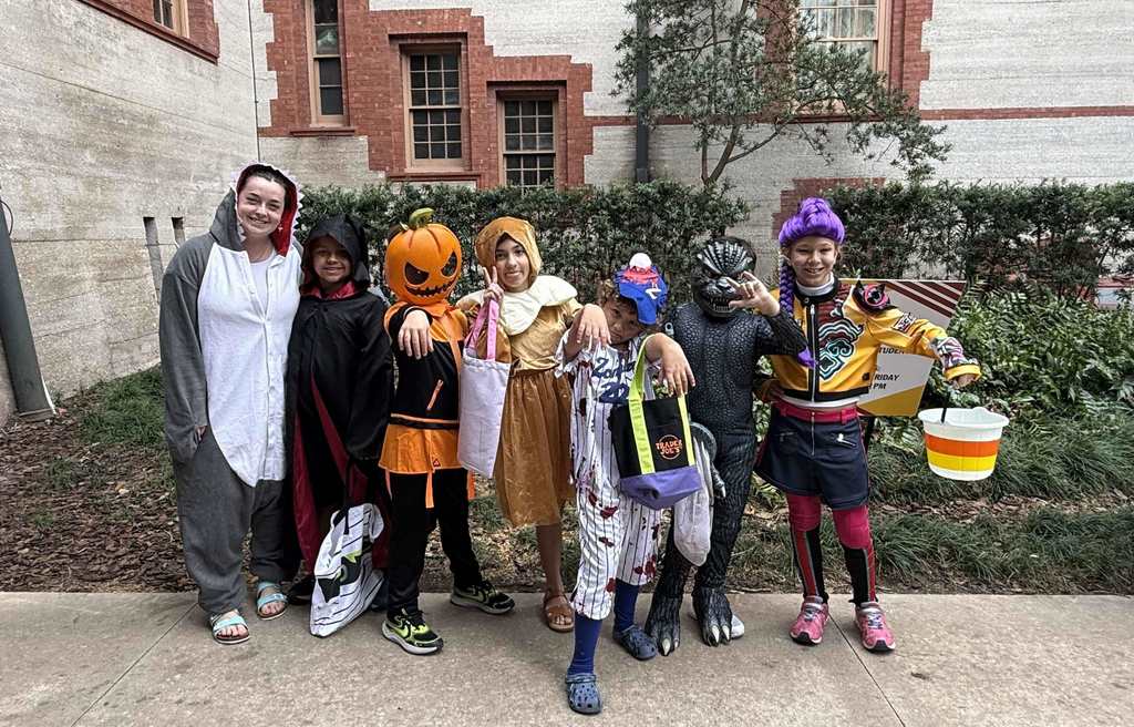 Group of dorm staff dressed up for Halloween along with the students smiling for a photo outside of Flagler College,.