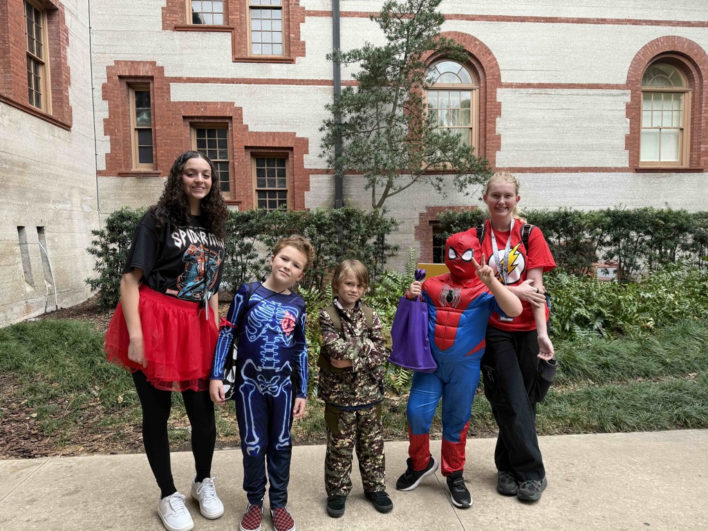 Group of dorm staff dressed up for Halloween along with the students smiling for a photo outside of Flagler College,.