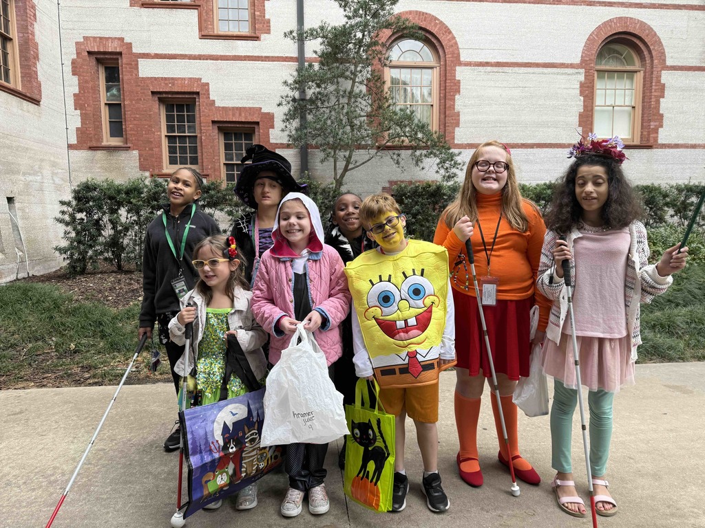 Group of dorm staff dressed up for Halloween along with the students smiling for a photo outside of Flagler College,.