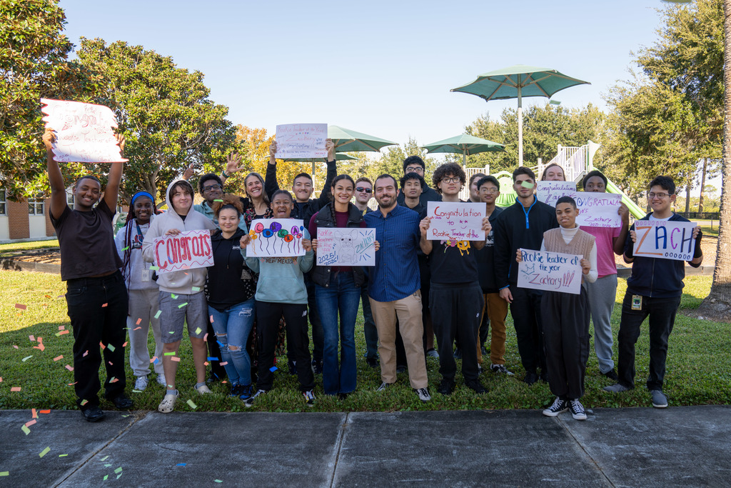 Zachary with his students - the students are holding various signs congratulating Zachary.