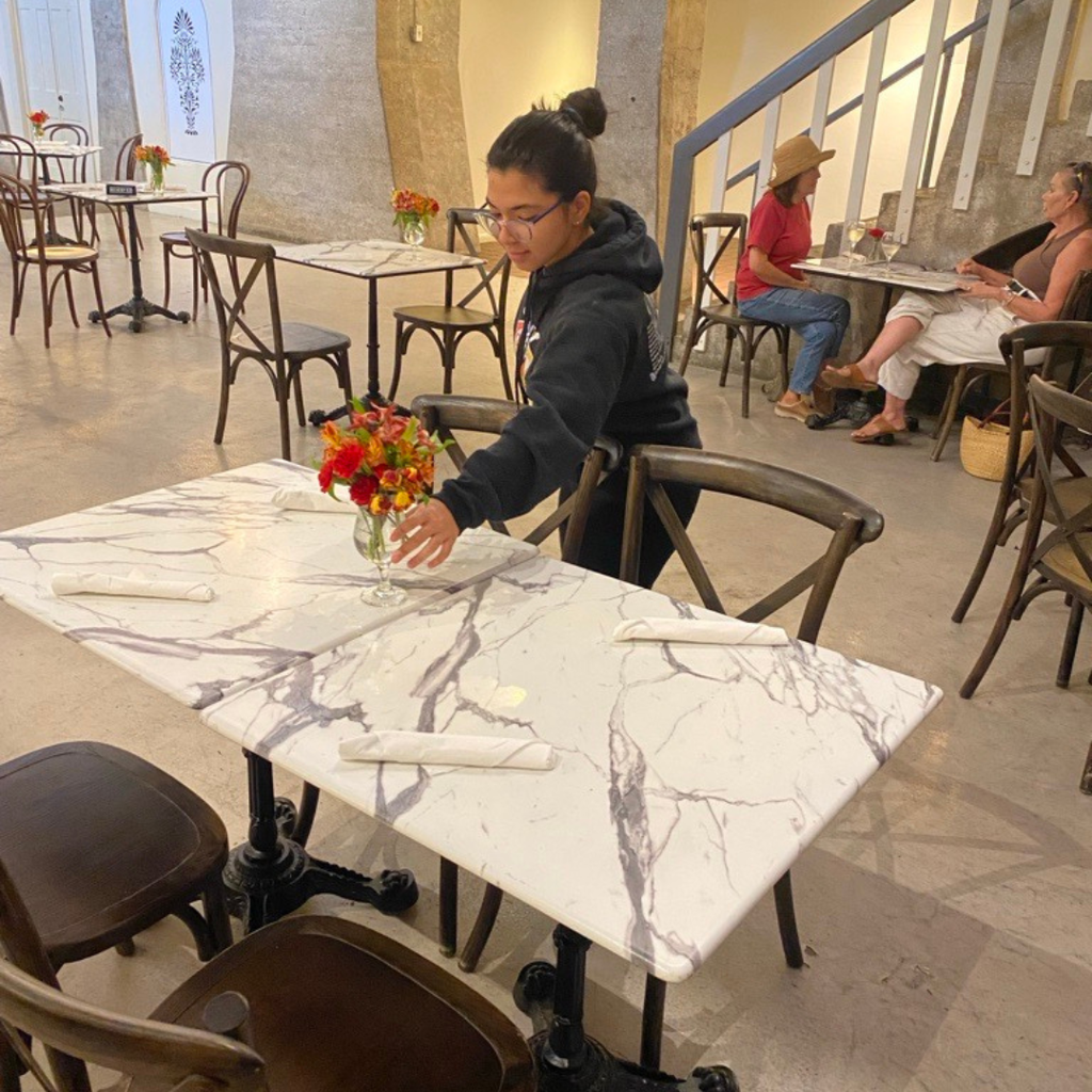 A student worker is setting up tables at a restaurant.