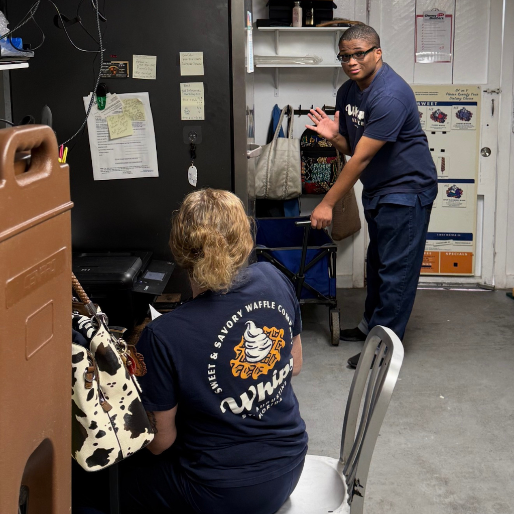A student worker is waving at the camera at his job.