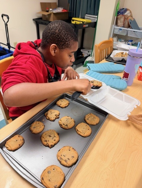 Billy putting the cookies he baked into a container. 