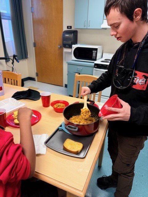 Aubrey scooping up the hamburger helper meal into the bowls. 