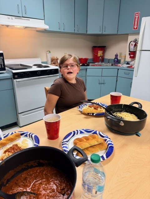Maddie smiling as she eats the meal that she had made. 