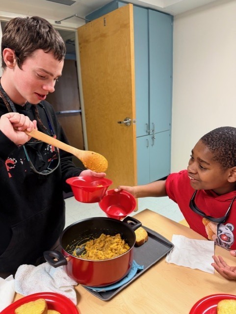 Billy and Aubrey helping each other putting hamburger helper food into bowls. 