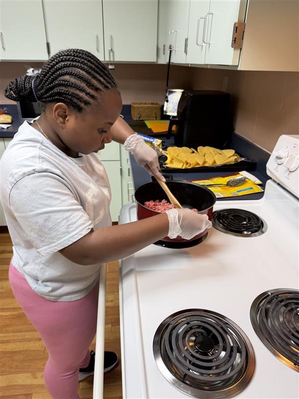 A student is working on browning the ground beef inside the Cary White kitchen.