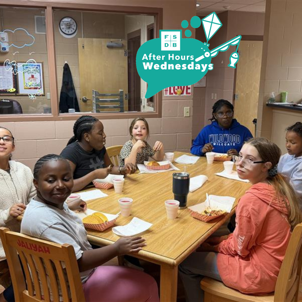 Blind middle schoolers sit at a table smiling for a photo while eating tacos for dinner inside Cary White. 