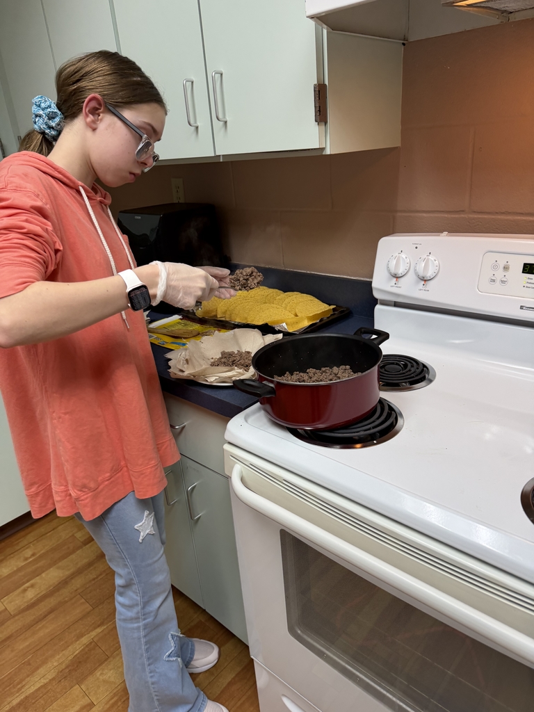 A student is scooping taco beef and putting them into shells inside the Cary White kitchen..