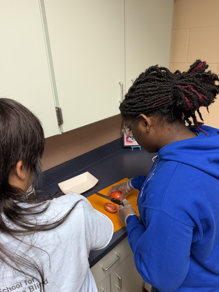 Two students work on cutting tomatoes inside the Cary White kitchen. 