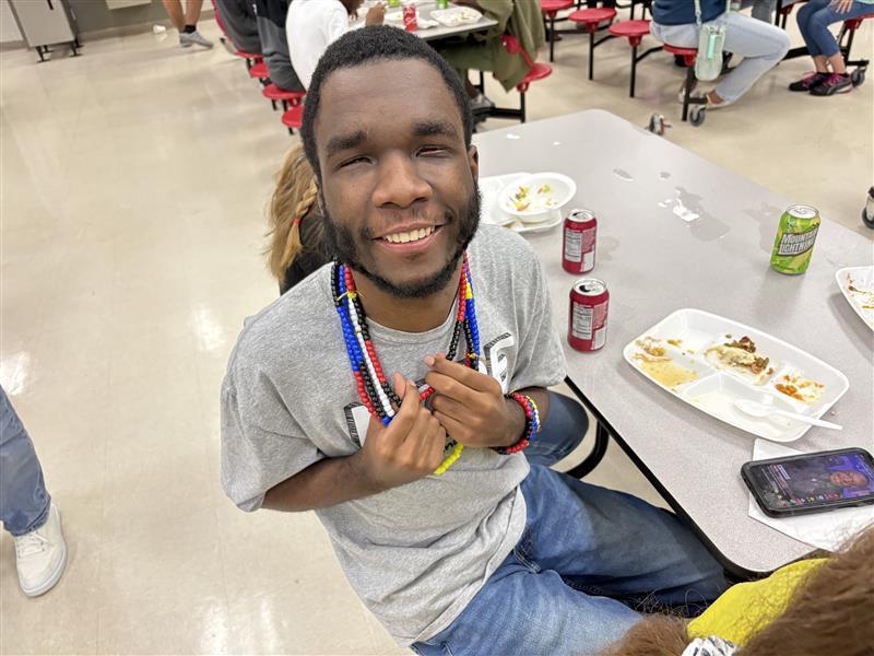 A student smiles sitting down with his thanksgiving meal inside the cafeteria.