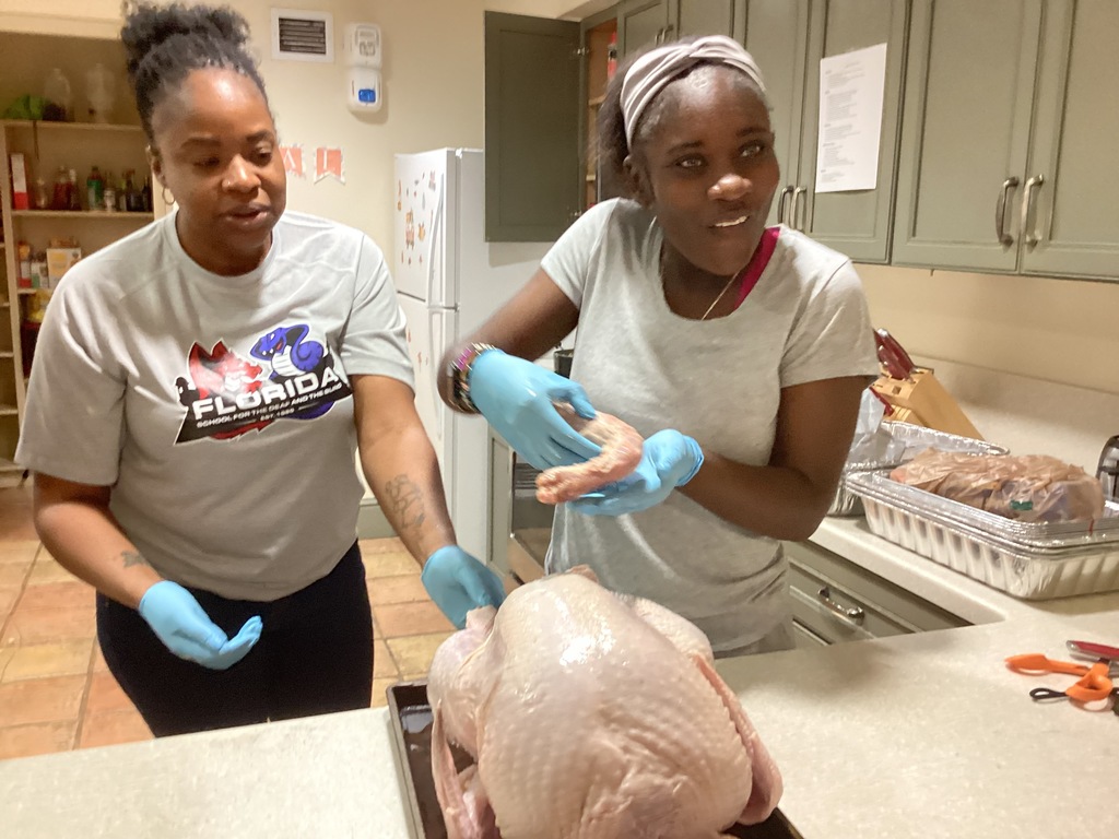 A student is shocked as she pulls the leg out of the turkey inside the apartment kitchen.