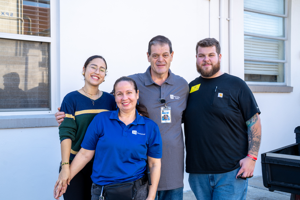 Joe Carbone wearing a gray shirt standing with his son, Nick (wearing a black shirt), his wife Rosa (big smile, wearing a royal blue shirt) and their daughter Maria with a big smile. Both Maria and Rosa also work on the FSDB campus!