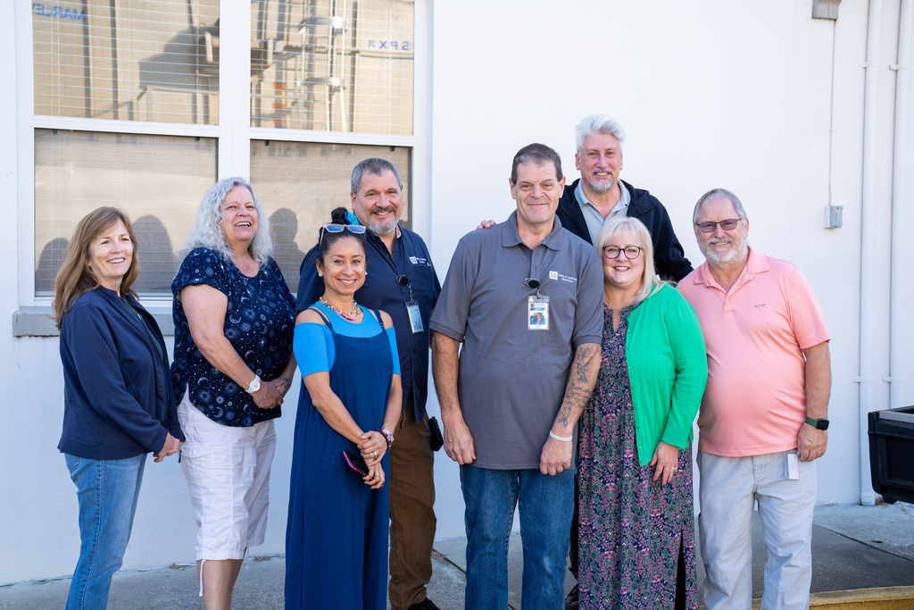 The other picture is outside of the Hogle building with members from Business Services/SaFO.  Pam Corey (navy blue jacket and jeans, brown hair is down), Pamela Campbell (White capris and a navy blue and white shirt with a big smile), Guy Maltese (navy blue polo shirt and khaki pants), Ray Casson (black jacket and gray shirt), Jess Voorhees (Light blue shirt with a dark blue jumper), Joe Carbone (gray polo shirt and jeans), Julia Mintzer (pink, navy and green dress with a green cardigan) and Addison Burns (pinkish shirt with light khaki pants).  All have big smiles on their faces!