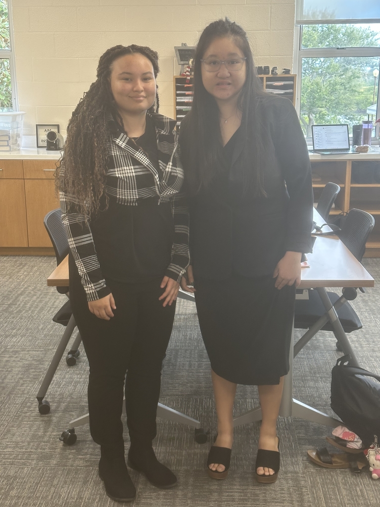 Two students dressed up nicely smile for a photo inside the classroom.