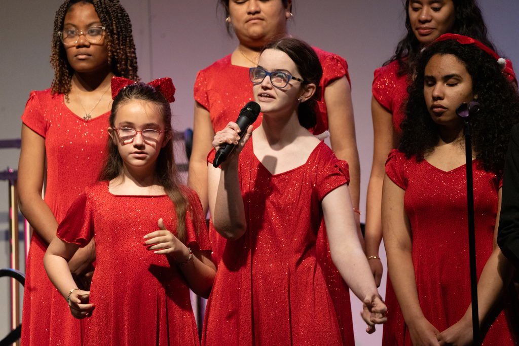 Group of students wearing red dresses sing on stage in the Music building.