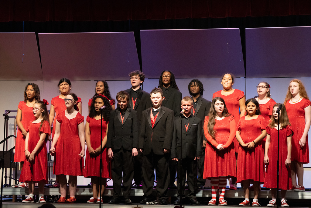 Group of blind students dressed in red dresses and black suits sing on stage in the Music Building.
