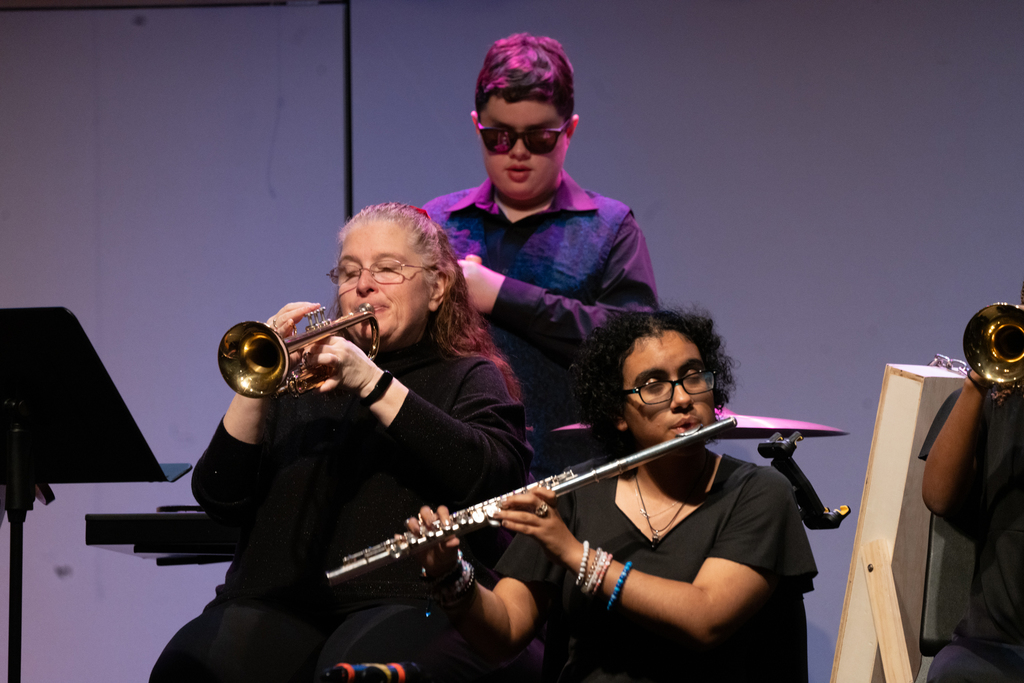 A music teacher and a student play band instruments on stage in the Music building.