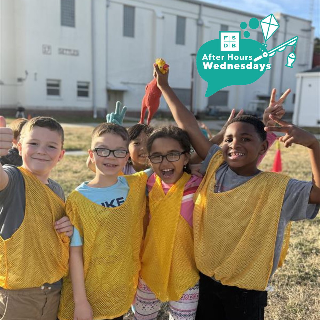 Group of Deaf Elementary students wearing yellow jerseys and pose for a photo with a chicken toy outside of Settles.