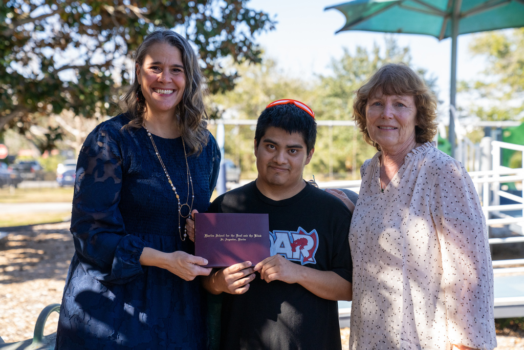 President Snow smiling with Max and his Mom outside on Kramer playground. 