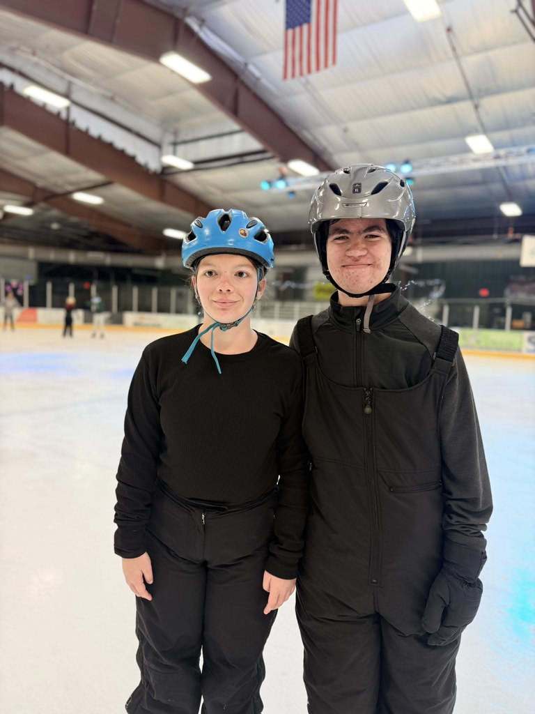 Two blind students smile together for a photo on the ice skating rink. 