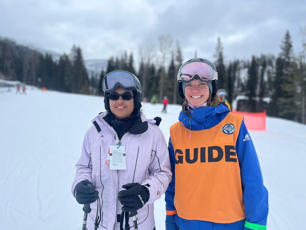 A student smiles with a guide on the slopes outside the snowy mountain. 