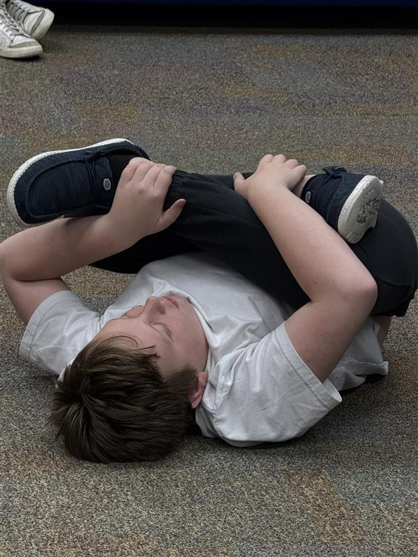 Blind student doing yoga in the hallway of Cary White.