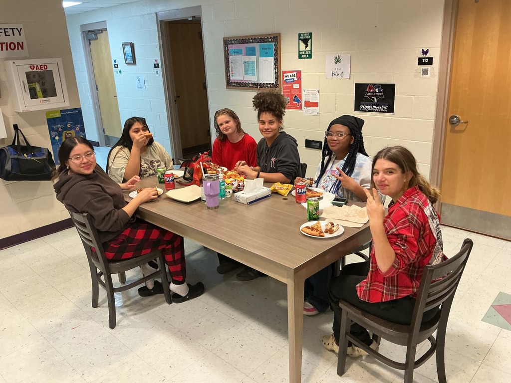 Group of dorm students smile for a photo eating food while watching the Super Bowl.