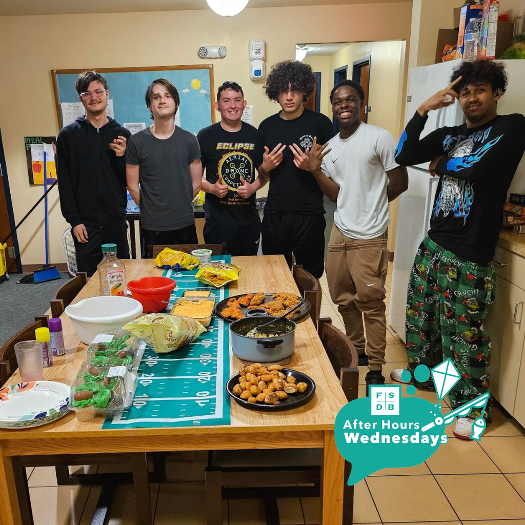 Group of boys dorm students smile for a photo by their Super Bowl food inside the dorm.
