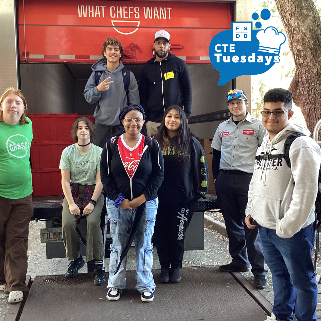 Group of culinary students smiling with the delivery truck outside. 