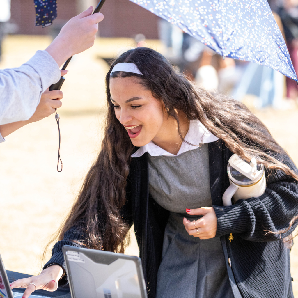 A SOAR student looking through other students work outside under an umbrella
