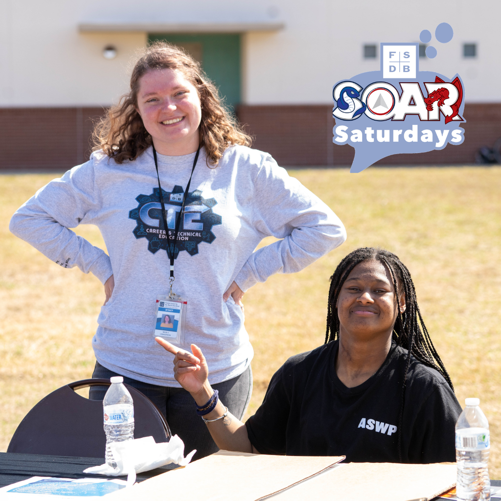 A staff member smiles with a SOAR student outside.