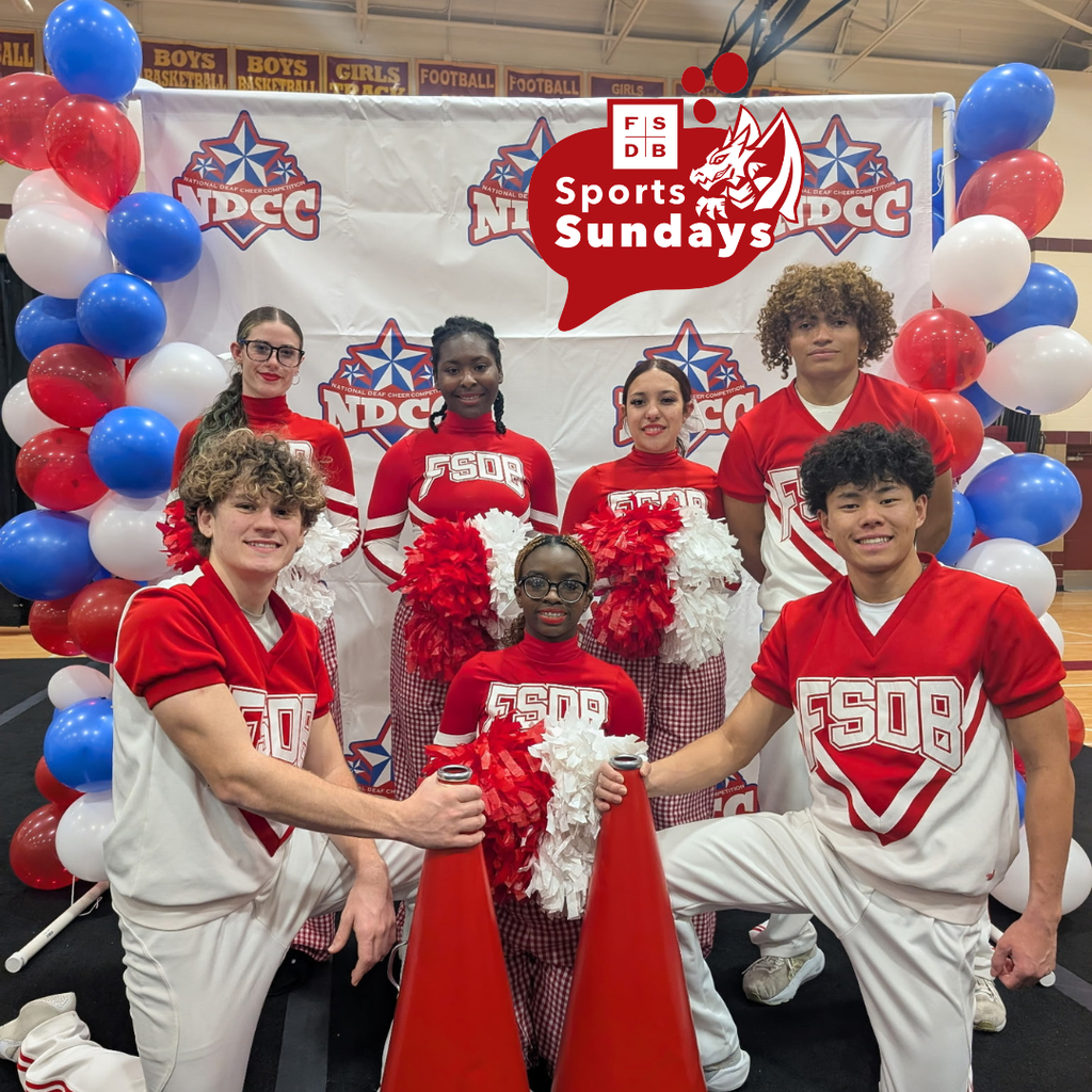 FSDB competitive cheerleading squad smile for a photo in front of NDCC banner inside the gym at Iowa School for the Deaf.