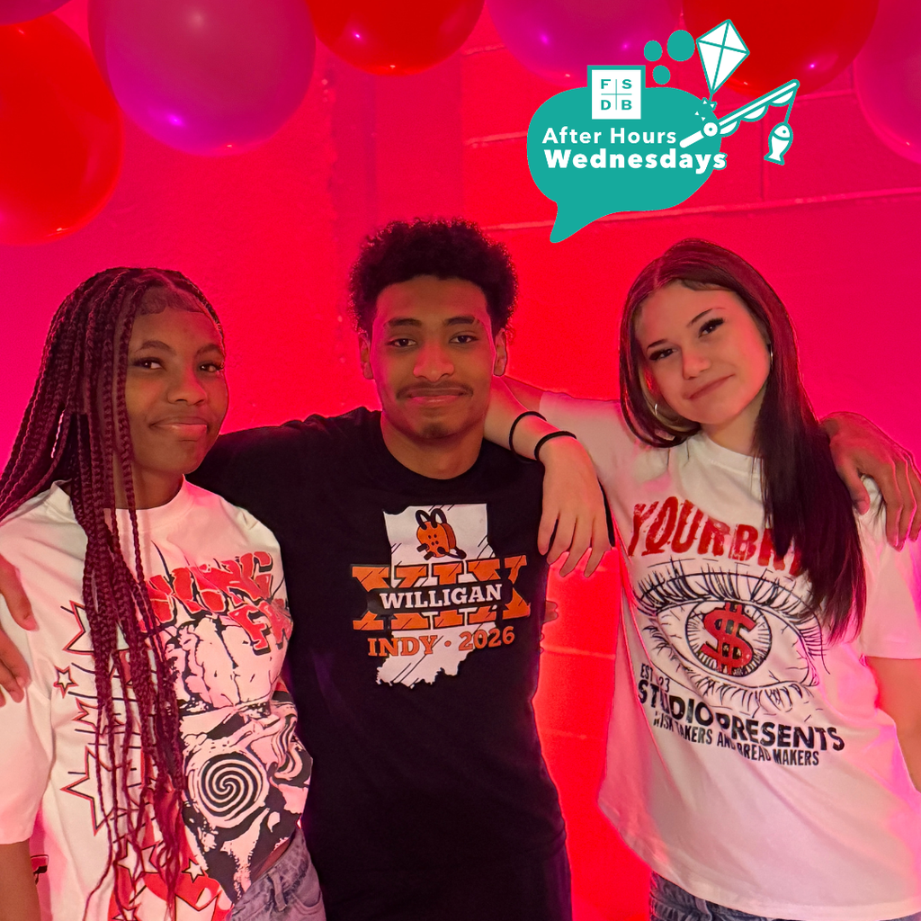 Three students smile for a photo together in front of a red valentine backdrop.