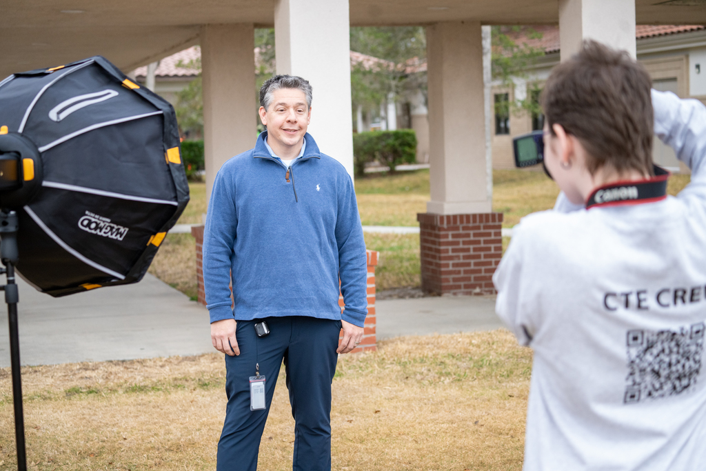 A student taking a staff member photo outside.