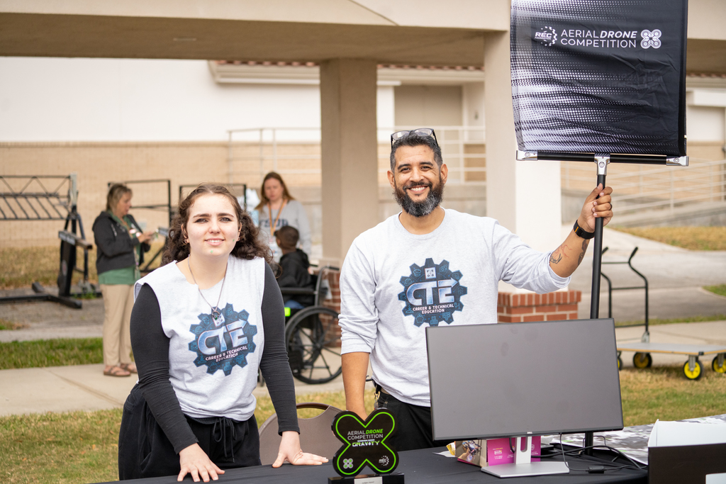 A student and staff member smile for a photo at the drone table.