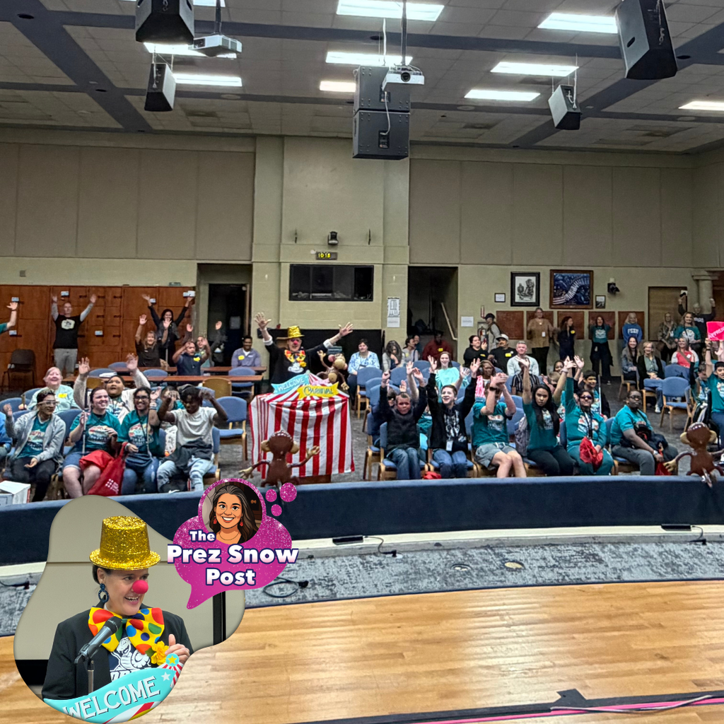 Photo description: A large group of students from the Blind Department along with staff and families sit in the Music Building, smiling and waving enthusiastically toward the stage. At the front of the room is a festive circus‑themed setup including colorful props. The atmosphere is lively and joyful, with everyone appearing excited to participate in the FSDB Braille Challenge. In the lower corner of the image, an inset graphic shows President Snow dressed as a cheerful circus ringleader wearing a glittery gold hat, red nose, and multicolored clown bow tie, speaking at a microphone with a welcoming sign below.