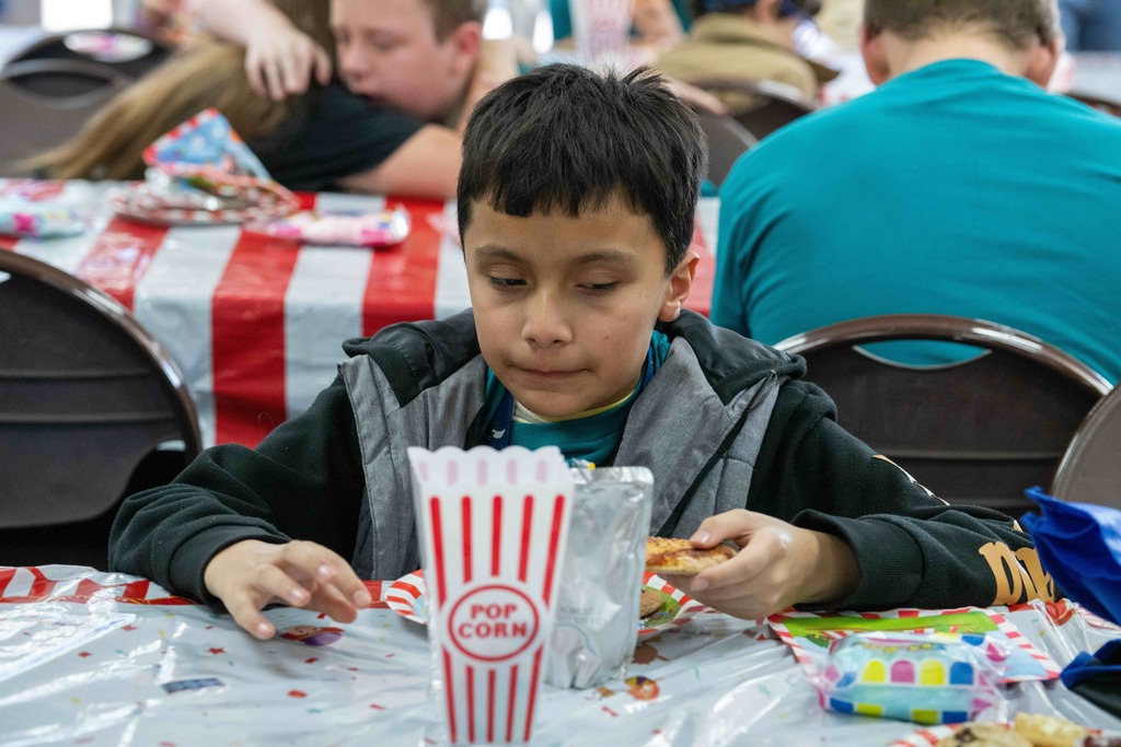 A student sitting during lunch time with his pizza and popcorn container. 