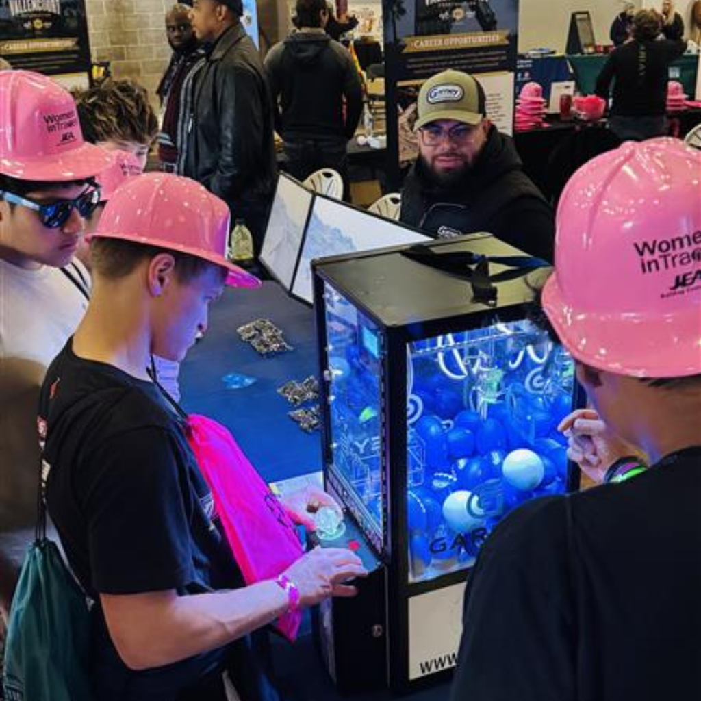 FSDB students wear pink construction hats and looking at exhibits inside. 