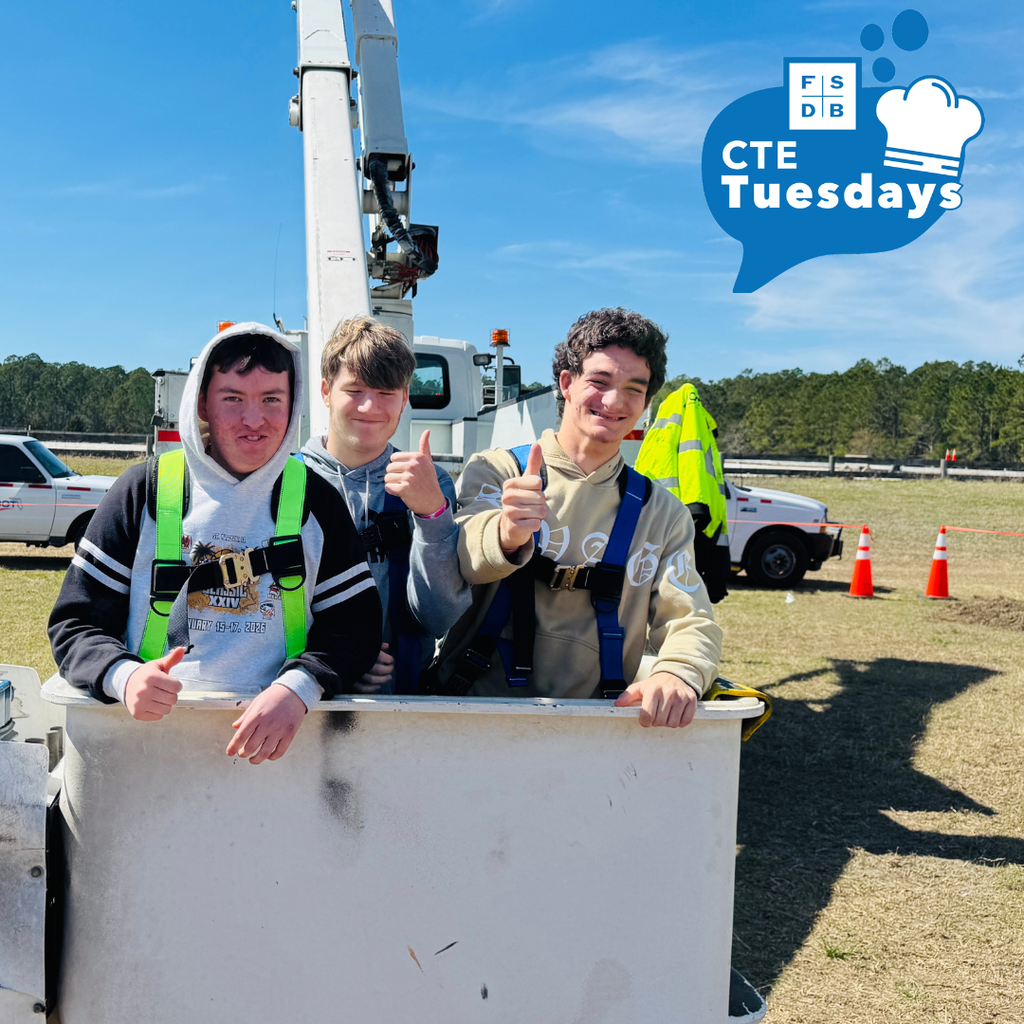 Three students hold their thumb up and smiles for the photo outside. 