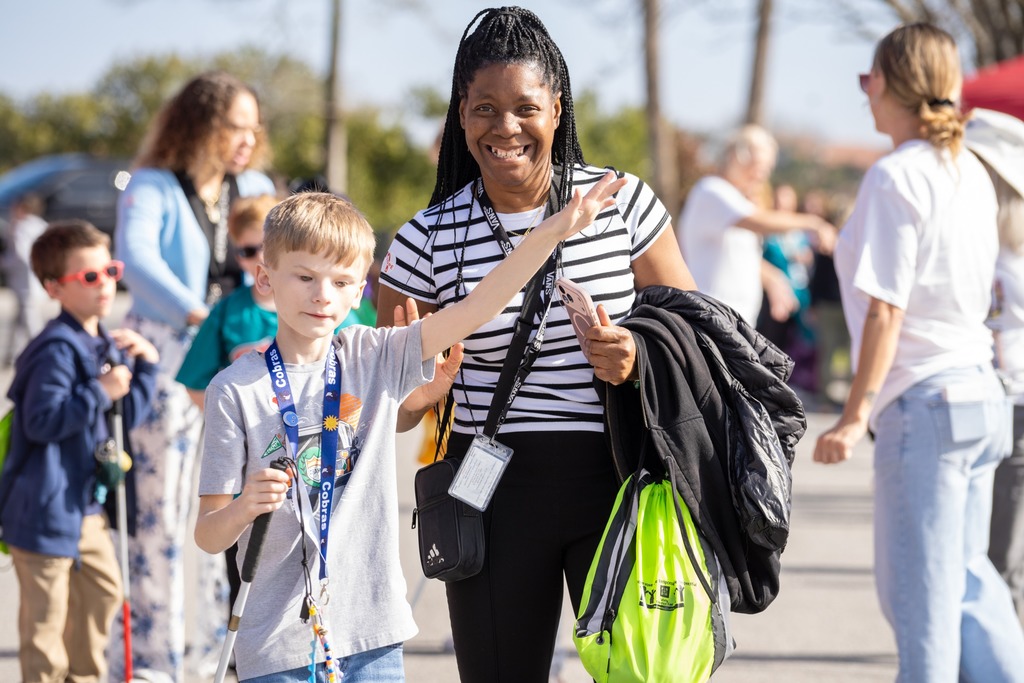 A student and staff member walks and smiles  for a photo. 
