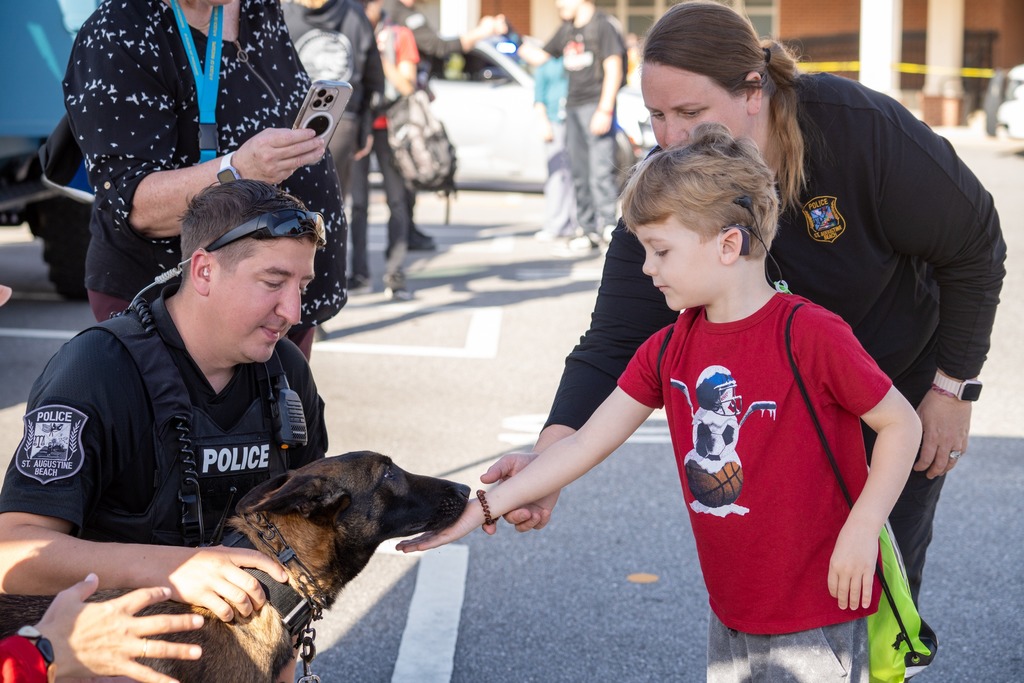 A student pets a German Shepard police dog. 