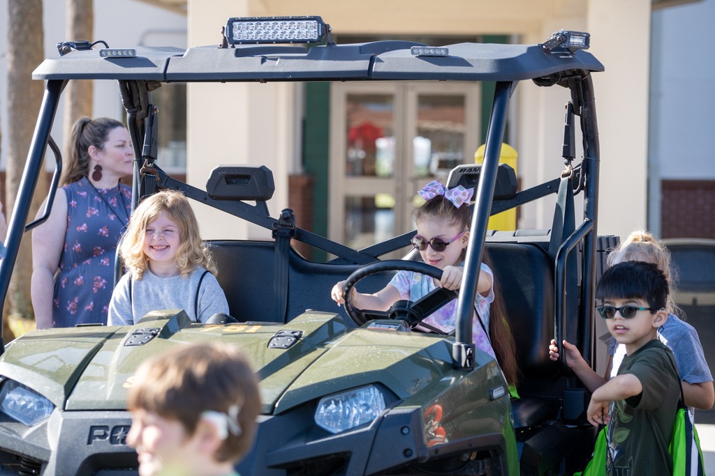 Students sit in a police golf cart smiles for a photo. 