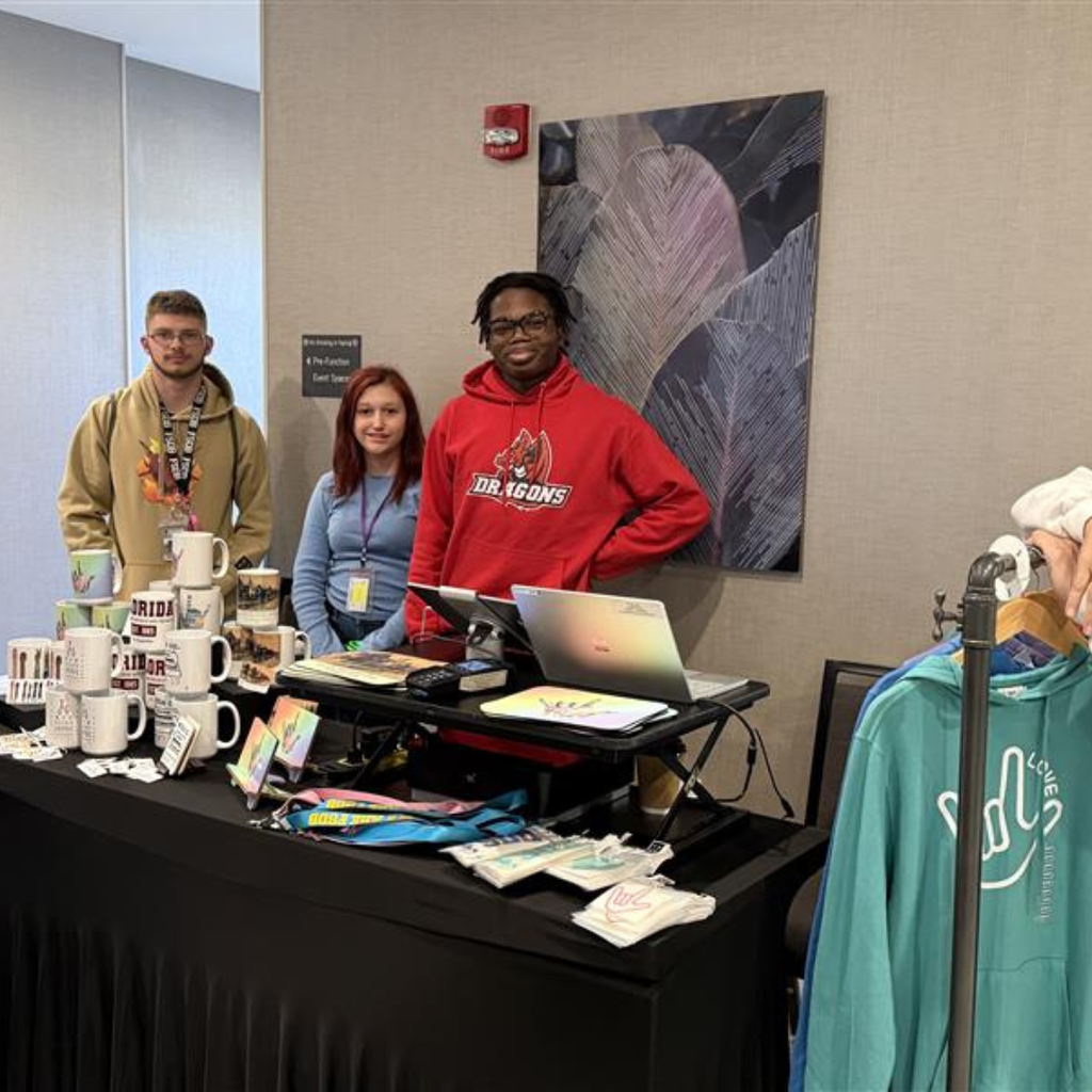 Group of students smile with the DB Designs merch inside the hotel building. 